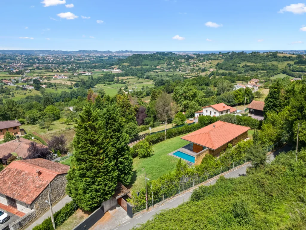 Vista de viviendas, jardines y paisaje de Caldones, con Gijón y el mar al fondo