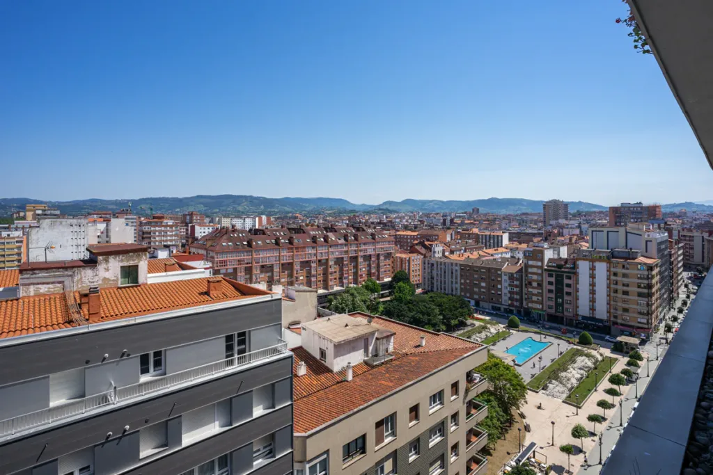 Vista elevada de edificios y del Parque de la Fábrica del Gas, con caminos, árboles y una lámina de agua.