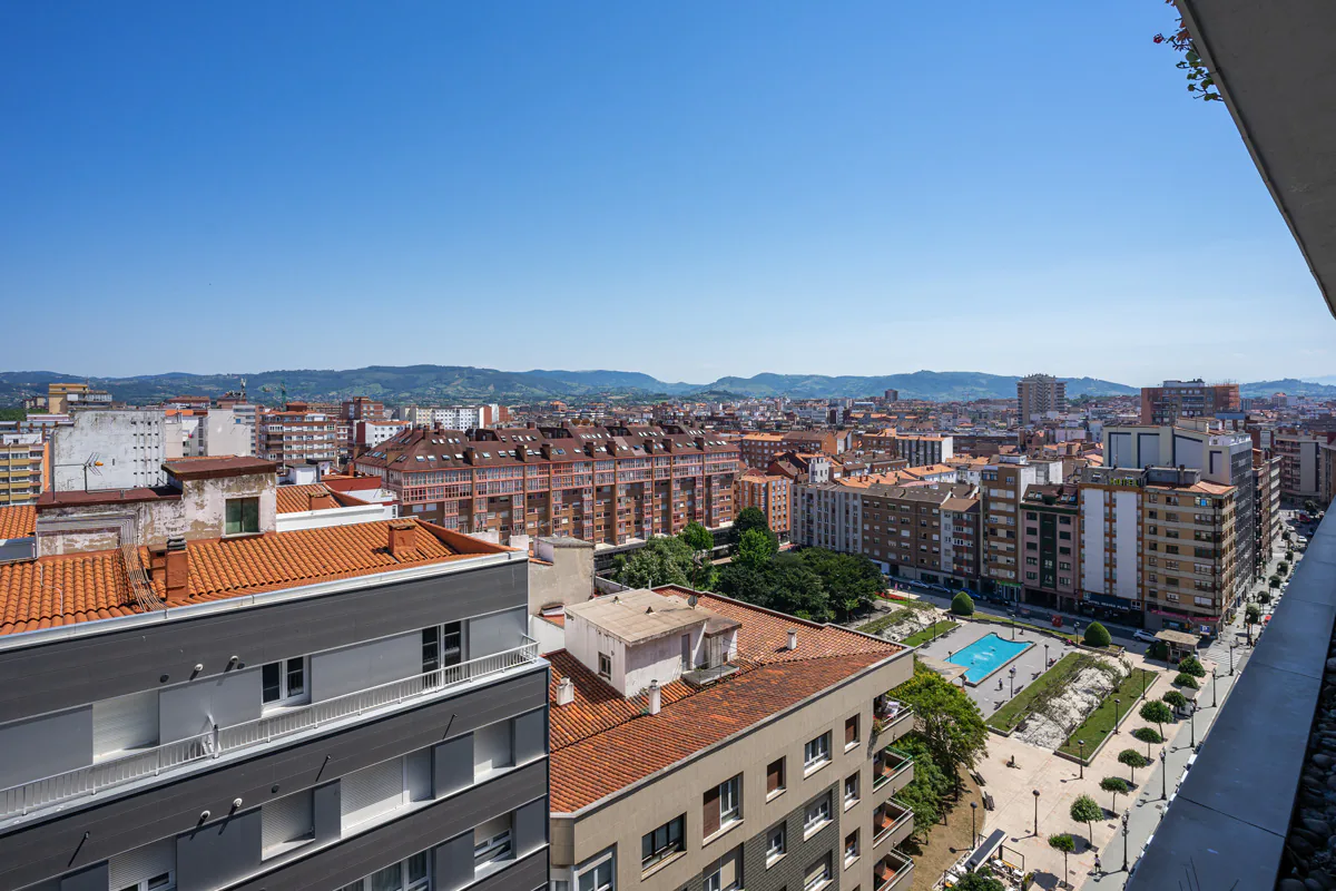 Vista elevada de edificios y del Parque de la Fábrica del Gas, con caminos, árboles y una lámina de agua.